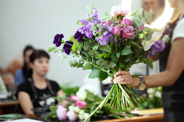 Female florist explain to students how to create bouquet at workplace. Floristics workshop.  Making beautiful flower bouquets and floral decorations.