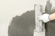 © New Africa - Closeup of worker spreading concrete on wall with spatula, space for text. Tile installation