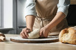 © New Africa - Female baker preparing bread dough at table, closeup