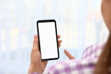Fototapeta  - Woman holding smartphone with blank screen on blurred background, closeup of hands. Space for text