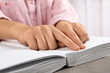 © New Africa - Blind person reading book written in Braille at table, closeup
