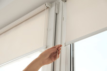 Woman Opening Modern Roll Blinds On Window In Room, Closeup