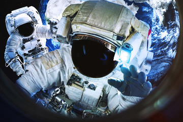Wall Mural - astronauts near the earth planet view in the illuminator of spaceship. science fiction. elements of 