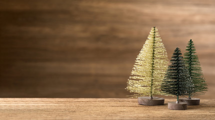 Poster - Christmas tree on wood table with wooden wall for merry chirstmas and new year holiday greeting card backgrond. banner mock up with copy space for display product.