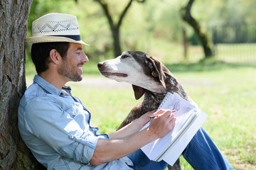 artist outdoors sketching picture of his dog