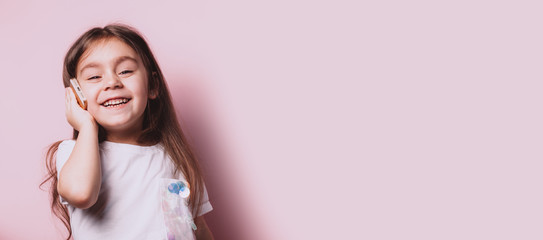 Happy little girl talking on telephone on pink background. Copyspace for your text.