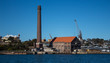 Factory brick smoke stack at historic dockyard and boat storage with crane against blue sky set on Cockatoo Island Sydney Harbour Australia