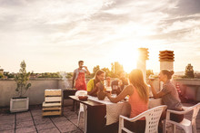 Young Friends Having Barbecue Party At Sunset On Penthouse Patio - Happy People Doing Bbq Dinner Outdoor Cooking Meat And Drinking Wine - Focus On Left Woman Face - Food, Fun And Friendship Concept