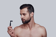 Everything Must Be Perfect. Handsome Young Man Shaving While Standing Against Grey Background