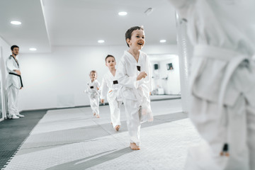 Wall Mural - Small group of children having training at taekwondo class. All dressed in doboks. White background.