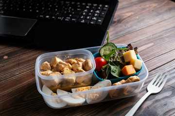 Healthy food in lunch box on working table with laptop