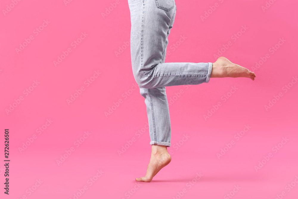 Stylish young woman in jeans on color background