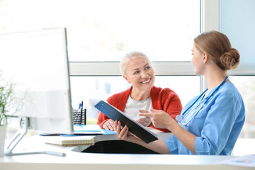 Medical assistant explaining mature woman her diagnosis in clinic