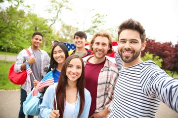 Group of students with USA flag taking selfie outdoors