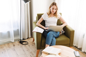 Poster - Beautiful young blonde woman sitting in armchair