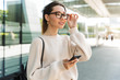 © Drobot Dean - Photo of brunette caucasian woman using cellphone while walking in big city street