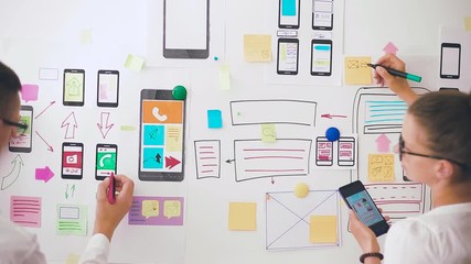 Aufkleber - Designers is developing a web application for mobile phones. Woman draws a mockup of interface to smartphone. User experience. 