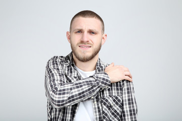 Poster - Young man having pain in shoulder on grey background