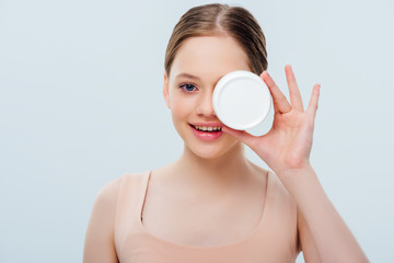 Wall Mural - happy teenage girl with obscure face holding cosmetic cream isolated on grey