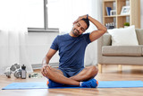 sport, fitness and healthy lifestyle concept - indian man training and stretching body at home