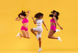 © Mike Orlov - Three strong and happy athletic women, jumping or dancing on yellow background wearing color sportswear. Fitness and sport motivation.