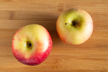 two beautiful red and yellow apples lie on a wooden background