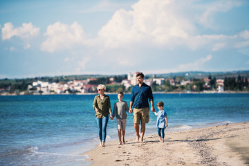 Wall Mural - Young family with two small children walking outdoors on beach.