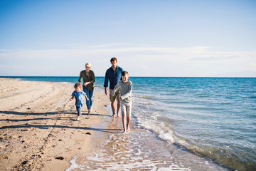 Wall Mural - Young family with two small children running outdoors on beach.