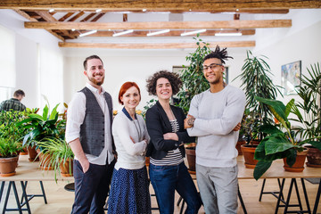 Group of young businesspeople standing in office, looking at camera.