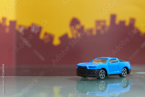 Fotografering  blue muscle car toy selective focus on blur city background