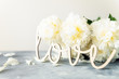 Bunch of amazing peonies in the vase and vintage wooden letters LOVE