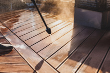 Man Cleaning Terrace With A Power Washer - High Water Pressure Cleaner On Wooden Terrace Surface