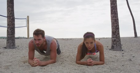 Wall Mural - Crossfit training fitness woman and man doing plank core exercise working out midsection muscles. Fit athlete fitness cross training planking exercising outside in summer on beach.