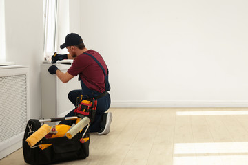 Wall Mural - Handyman in uniform working with screwdriver indoors, space for text. Professional construction tools