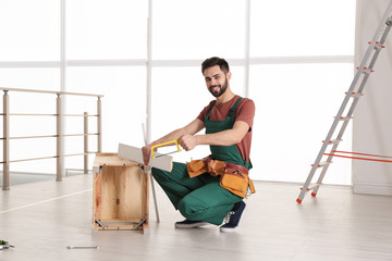 Wall Mural - Carpenter in uniform making furniture indoors. Professional construction tools