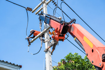 Two electrician workers are climbing on the electric poles to install and repair power lines.