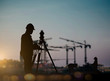© Yuttana Studio - silhouette engineer looking Loaders and trucks in a building site over Blurred construction worker on construction site