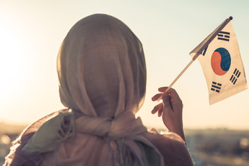 Wall Mural - Muslim woman in scarf with South Korea flag of at sunset. Concept