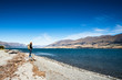 © ztony1971 - Tourist admires the view while stand next to Lake wanaka Boundary Creek with background of blue sky and rocky mountain with copy space.