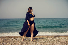Attractive Busty Curvy Woman In A Blue Swimsuit Resting On The Beach. Stylish Accessories, Fringe, Fashion For Plus Size, Beautuful Sea. Bodypositive, Natural Authentic Beauty, Resort, Summer Vacation