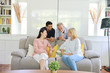 © feeling lucky - Happy elder multiethnic family meeting and talking on grey sofa in living room with laughing and smiling faces