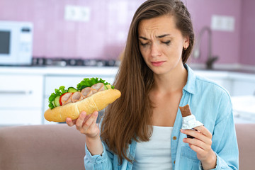 Unhappy stressed crying woman eating unhealthy food and chocolate because of depression and stress. Nerve food. Life problems and difficulties. Food addiction