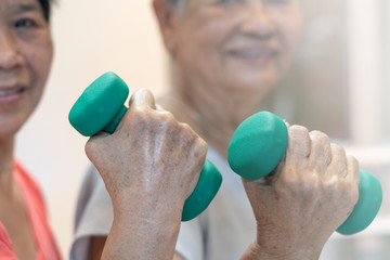 Strong and healthy senior old people holding  dumbbells for doing exercise or physical therapy in nursing home.