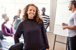 © Flamingo Images - Young designer smiling with office colleagues in the background