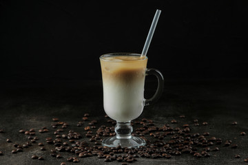 Ice latte or Iced coffee with milk and ice cubes in a glass beaker against a dark background. refreshing drink. summer drink.