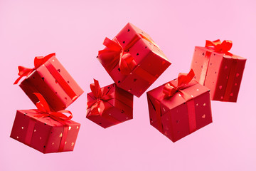 Many traditional gift boxes are falling on pink background. Festive season is bustle. Selection of gifts. Festive events.