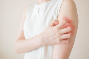 young woman scratching arm from having itching on white background. cause of itchy skin include inse
