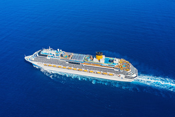 Aerial view of beautiful modern large white cruise ship liner with colorful deck against clear blue sea background. Top view from drone of floating liner