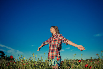 Beautiful girl in poppy field. Young girl with long hair among the blossoming poppy field. concept of freedom and travel. Poppy buds. Gardening