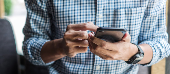 young casual businessman holding and using smartphone for sms messages, hipster man typing touchscre